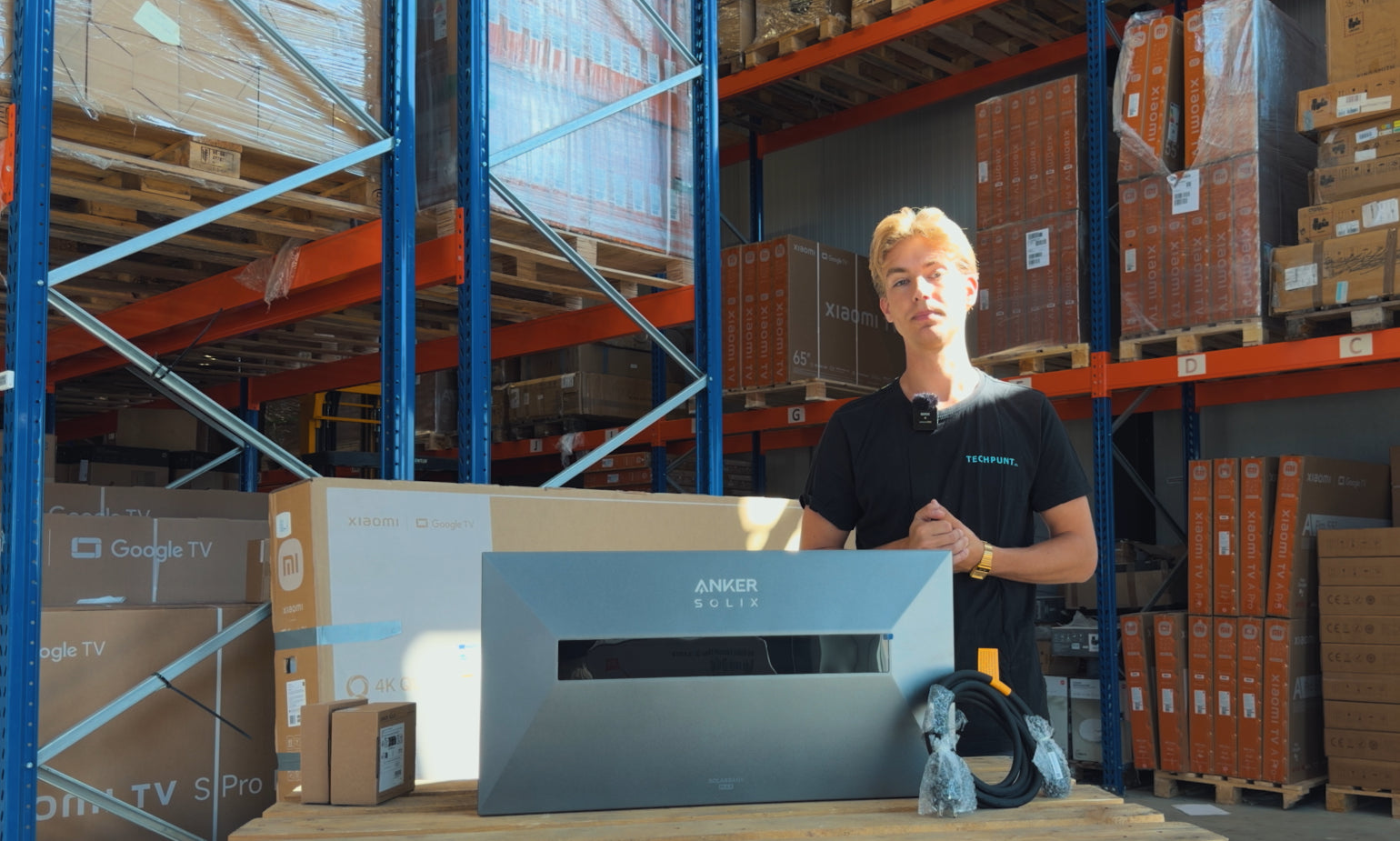 TechPunt medewerker presenteert de Anker SOLIX Solarbank Max AC thuisbatterij met meegeleverde accessoires in het magazijn.