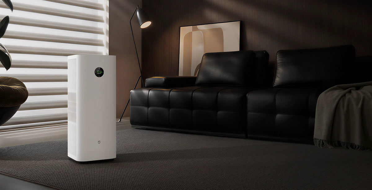 Xiaomi Mijia Smart Air Purifier 6 Plus naast een leren bank in een donkere woonkamer