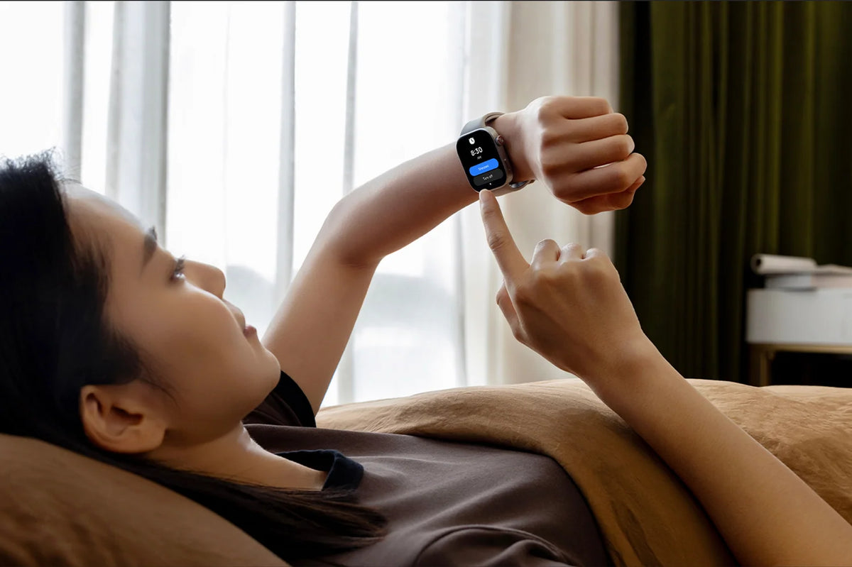 Vrouw kijkt in bed naar haar slaapgegevens op de Xiaomi Redmi Watch 6