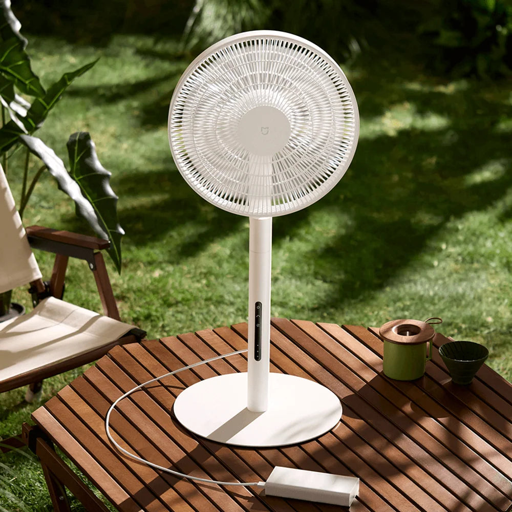 Xiaomi Mijia Smart Standing Fan Pro Slim buiten op een tuintafel tussen twee campingstoelen