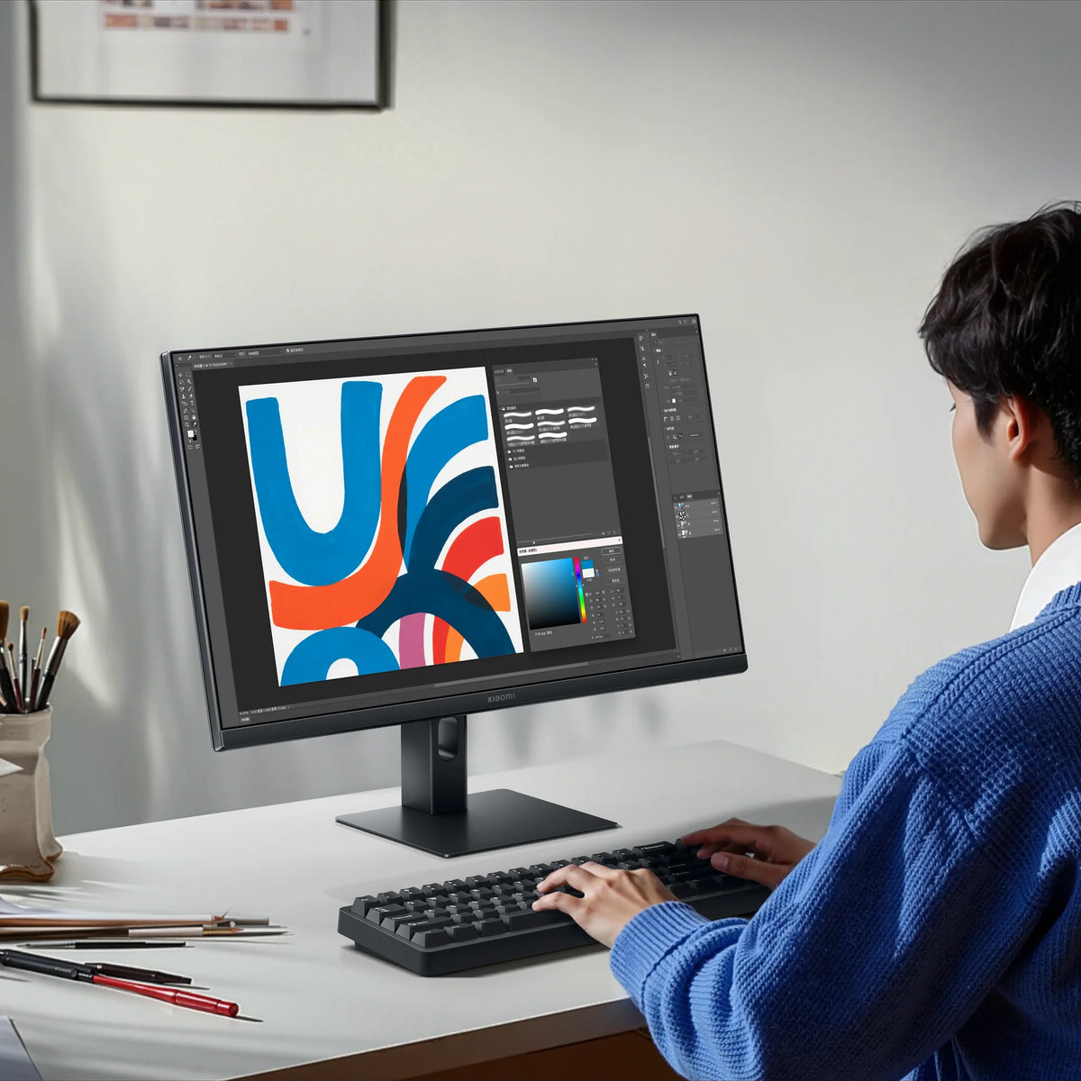 Iemand werkt aan een illustratie op de Xiaomi Monitor A24i 2026 aan een licht bureau