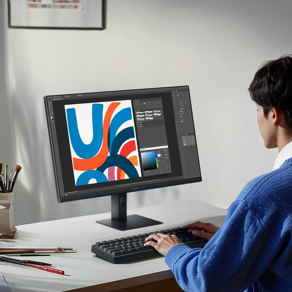 Iemand werkt aan een illustratie op de Xiaomi Monitor A27i 2026 aan een licht bureau