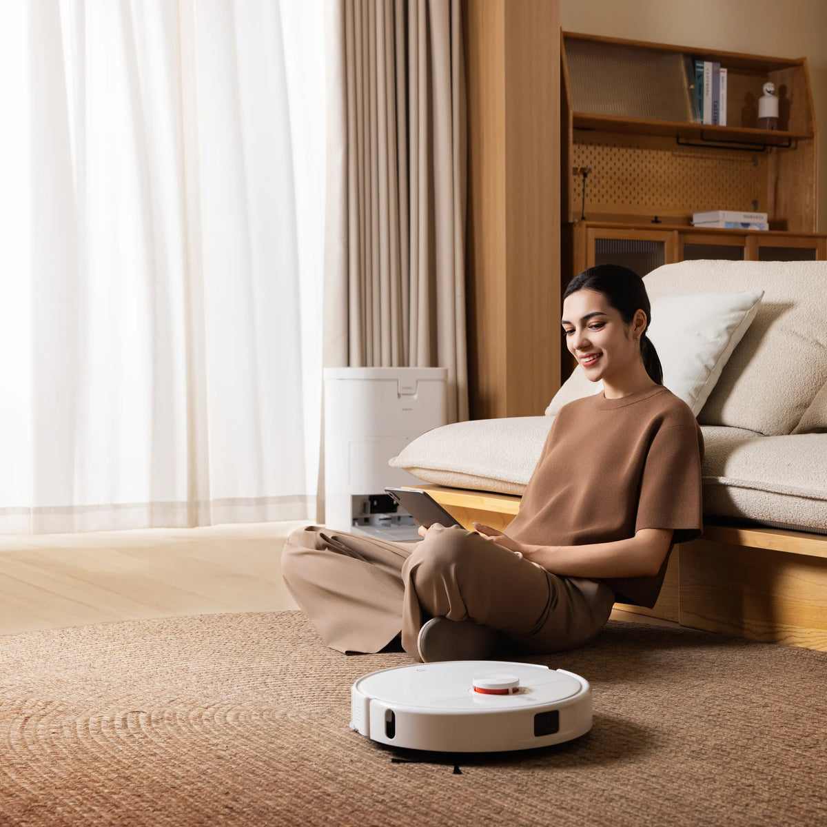 Xiaomi Robot Vacuum H50 rijdt over het kleed terwijl iemand tegen de bank zit
