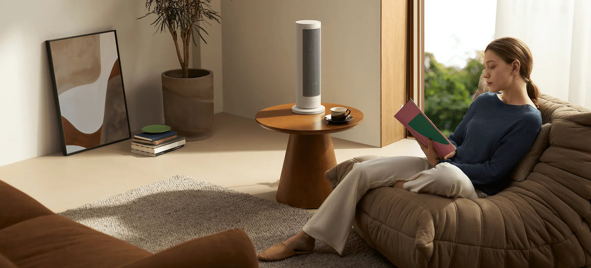Xiaomi Smart Graphene Heater op een bijzettafel naast een lezende vrouw in de woonkamer