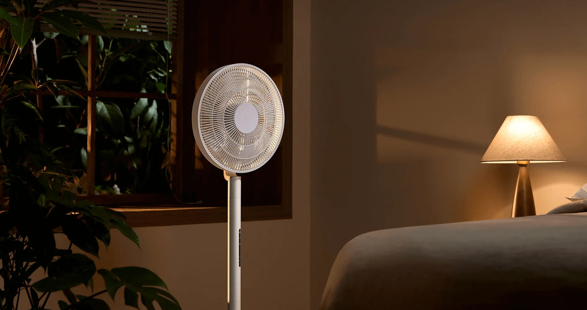 Xiaomi Mijia Smart Standing Fan Pro Slim in een schemerige slaapkamer naast een leeslamp