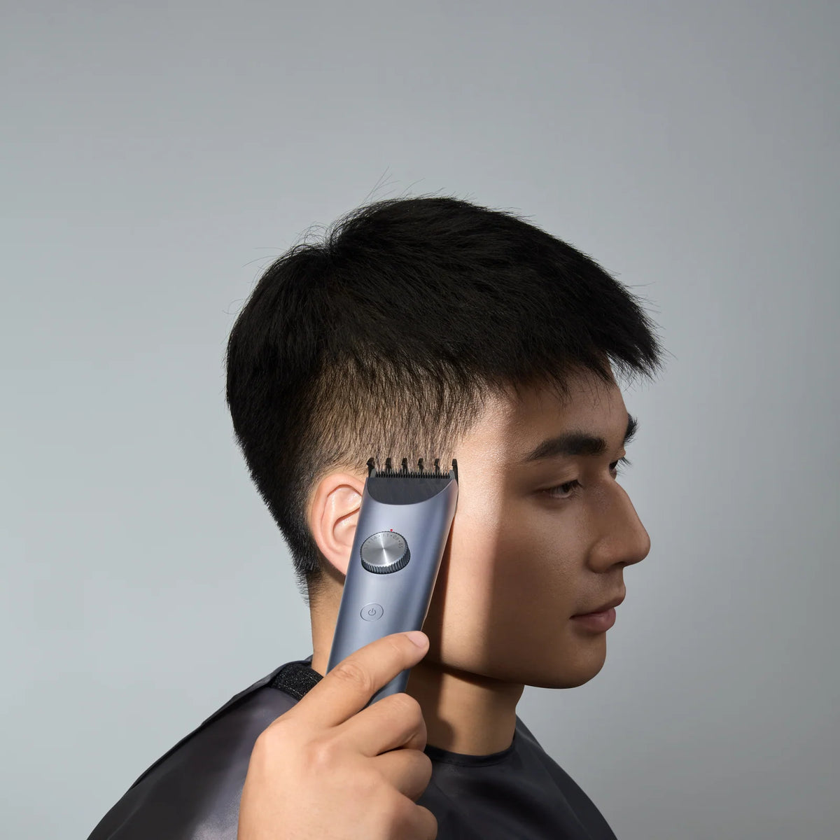Man knipt zijn haar met de Xiaomi Hair Clipper 2 en draagt de kapperscape
