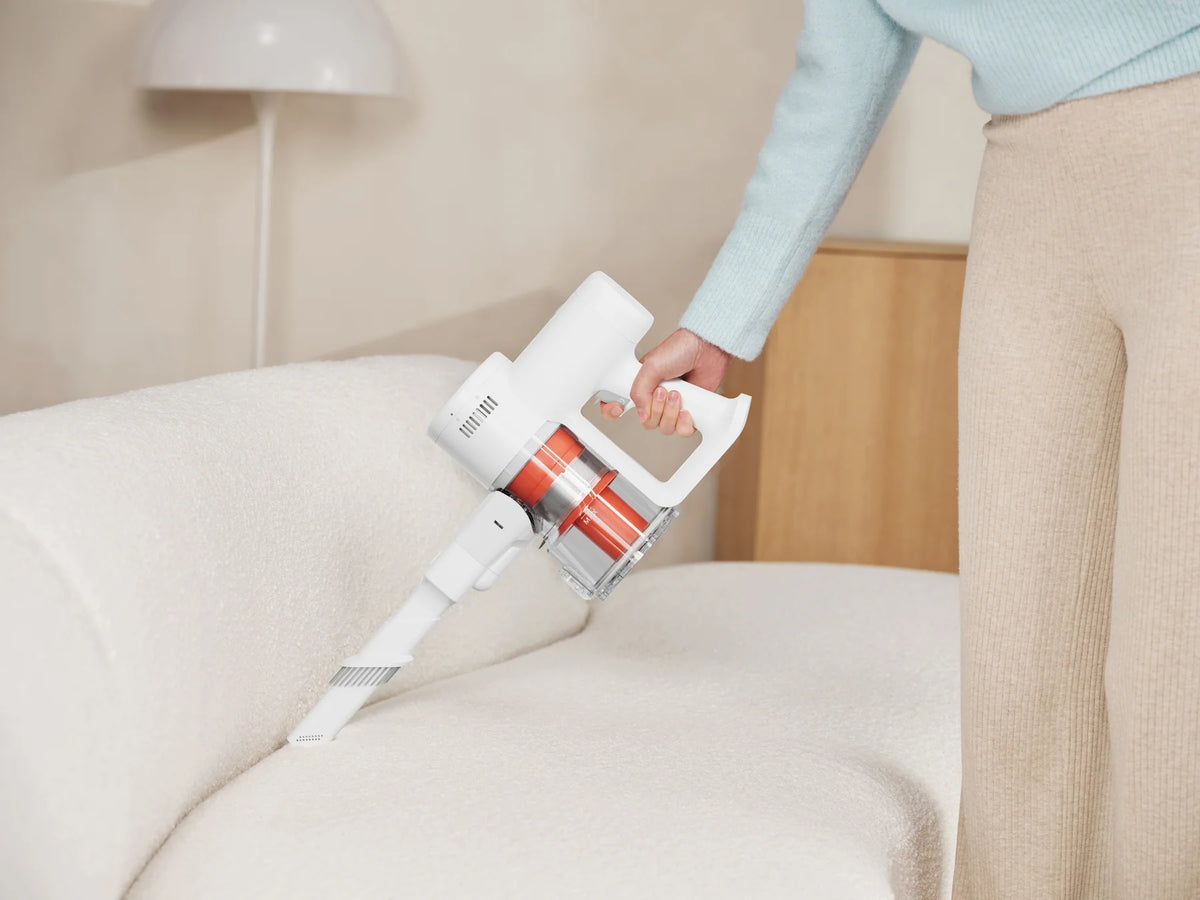 Vrouw zuigt de bank met de Xiaomi Mijia Vacuum Cleaner 4C als handstofzuiger