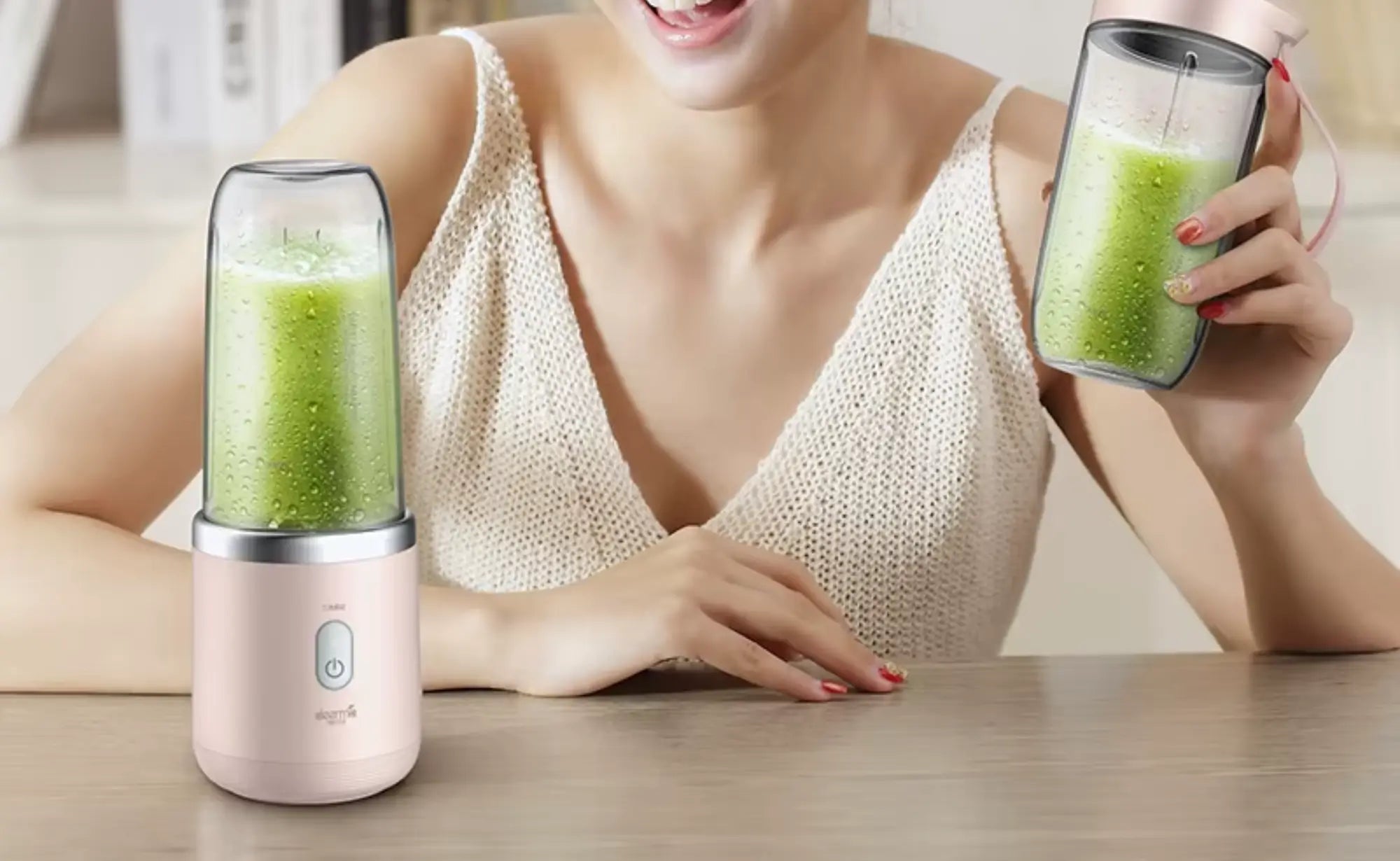 Vrouw met twee glazen groene smoothies uit Xiaomi personal blenders met draagbare drinkbekers