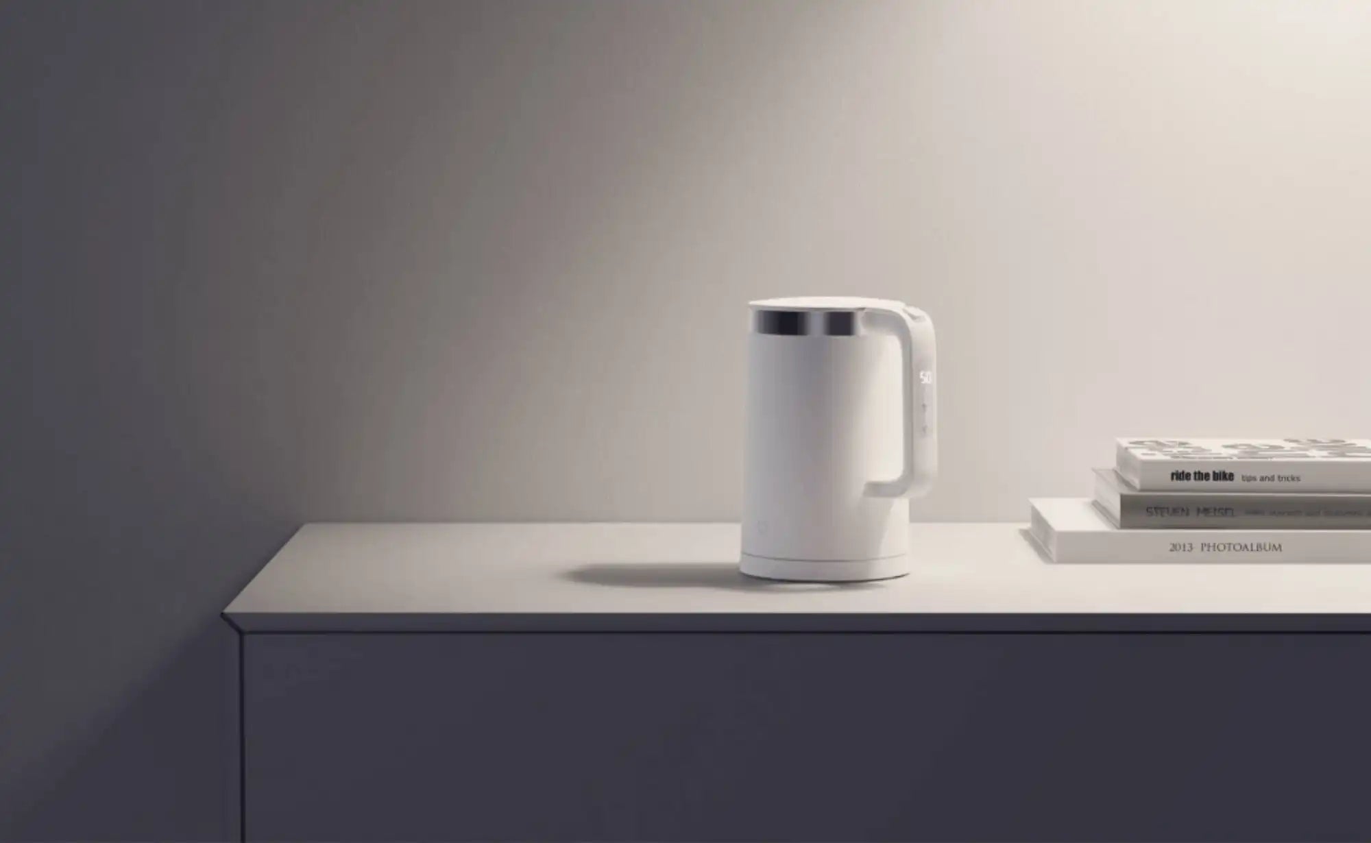 Witte Xiaomi waterkoker op een minimalistisch bureau naast boeken in een moderne interieur