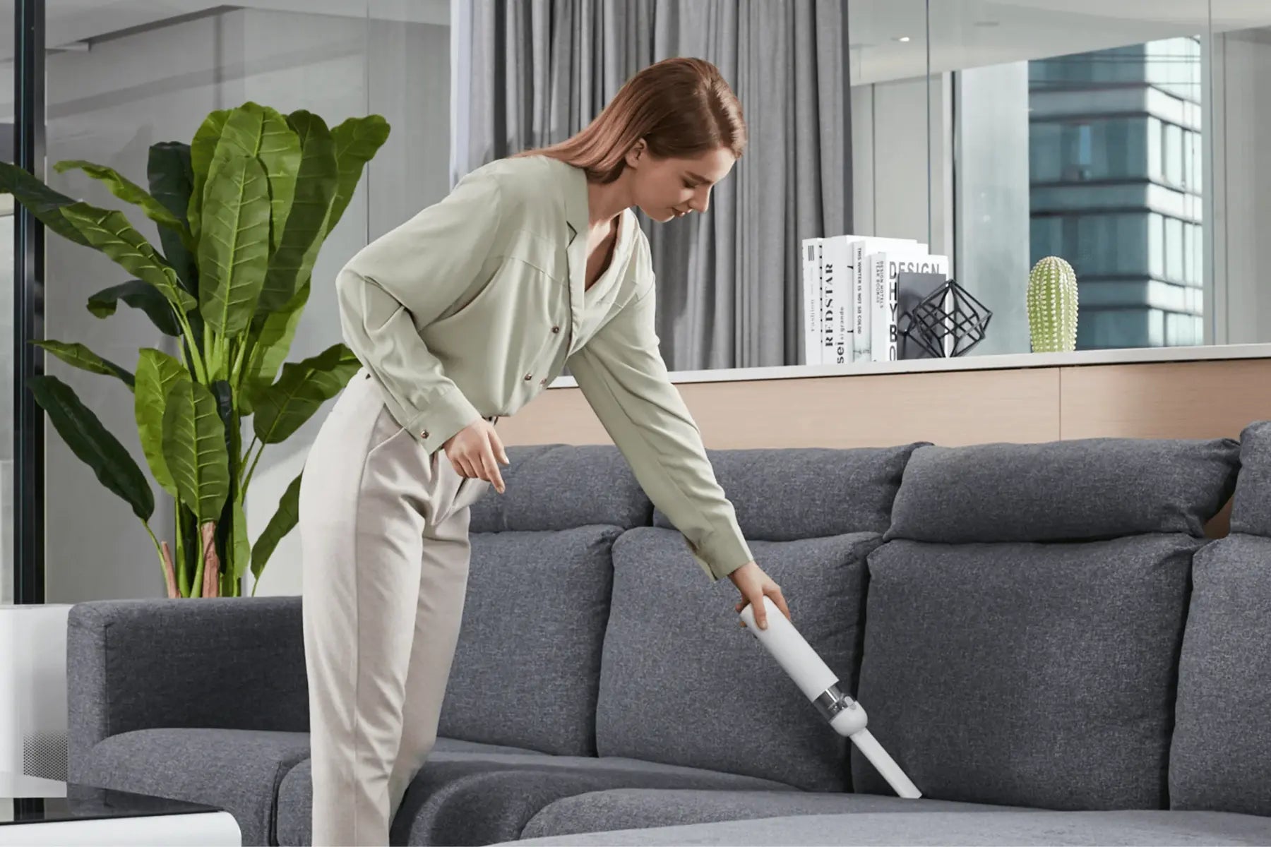 Vrouw zuigt de bank met een compacte witte Xiaomi handstofzuiger