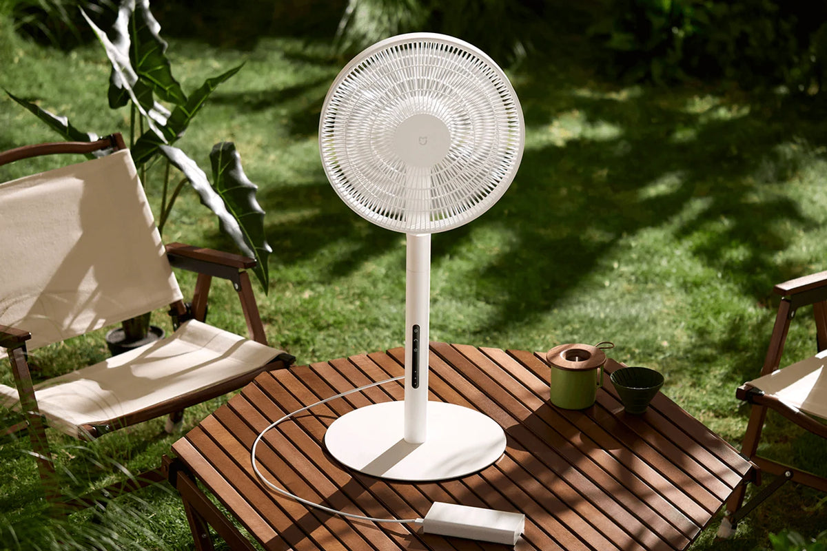 Xiaomi Mijia Smart Standing Fan Pro Slim op een tuintafel, aangesloten op een powerbank