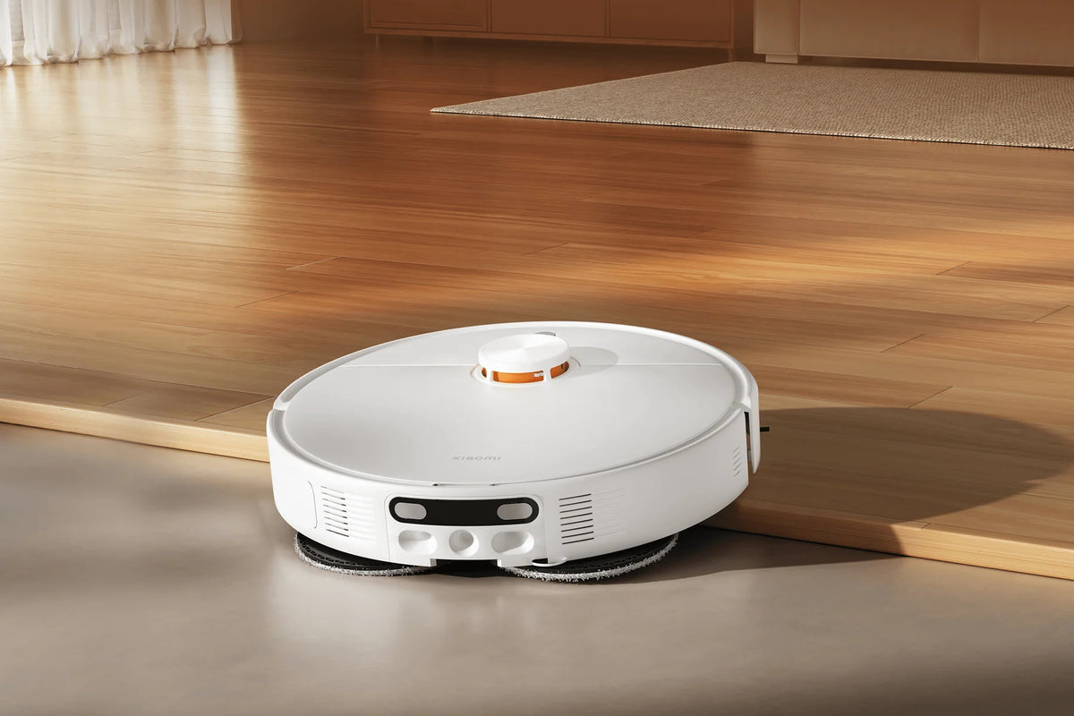 Xiaomi Robot Vacuum H50 op een houten vloer bij de rand van het tapijt