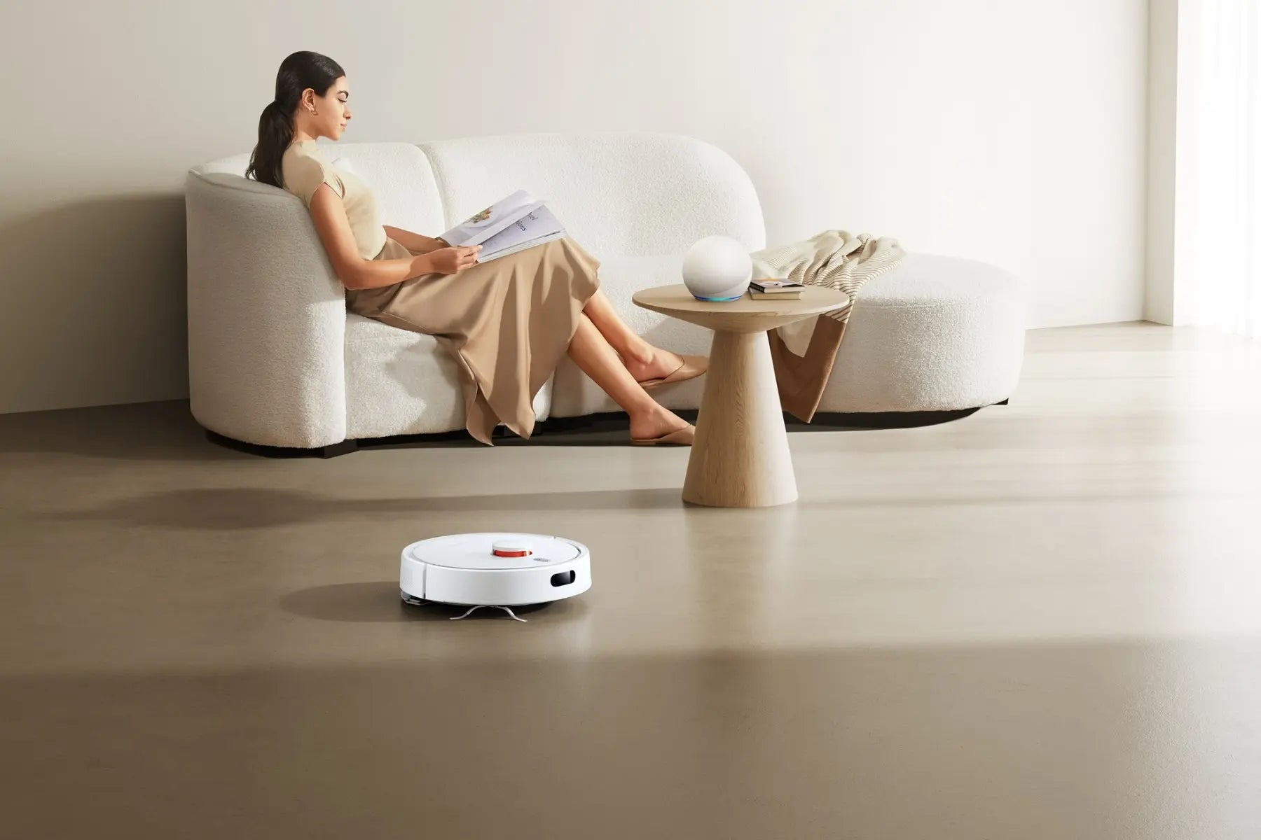 Xiaomi robotstofzuiger maakt automatisch de woonkamer schoon terwijl een vrouw op de bank leest