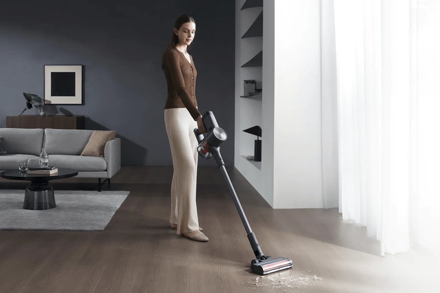 Vrouw stofzuigt de houten vloer met een draadloze Xiaomi steelstofzuiger