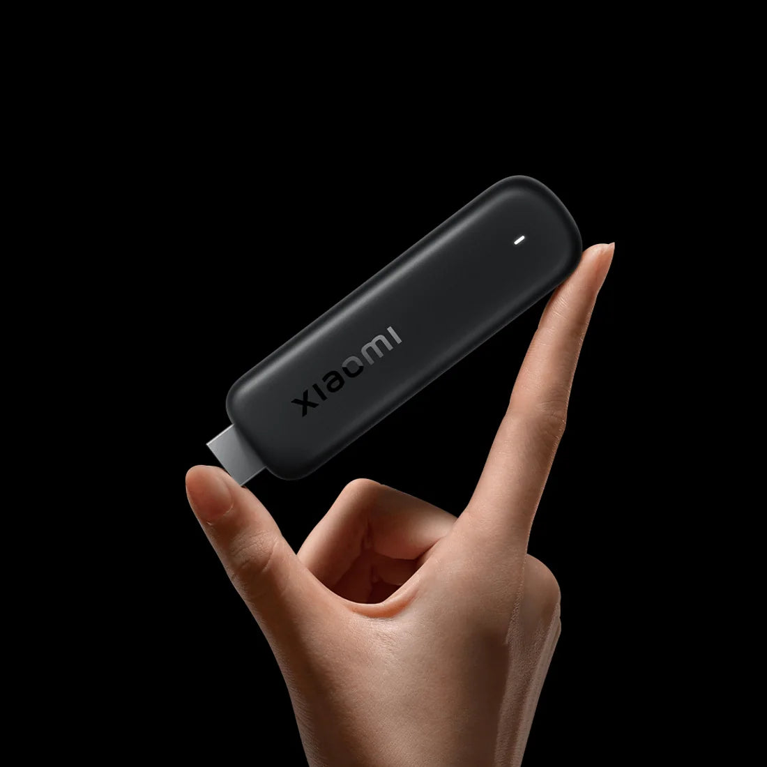 Xiaomi TV Stick HD (2nd Gen) tussen duim en wijsvinger op een zwarte achtergrond